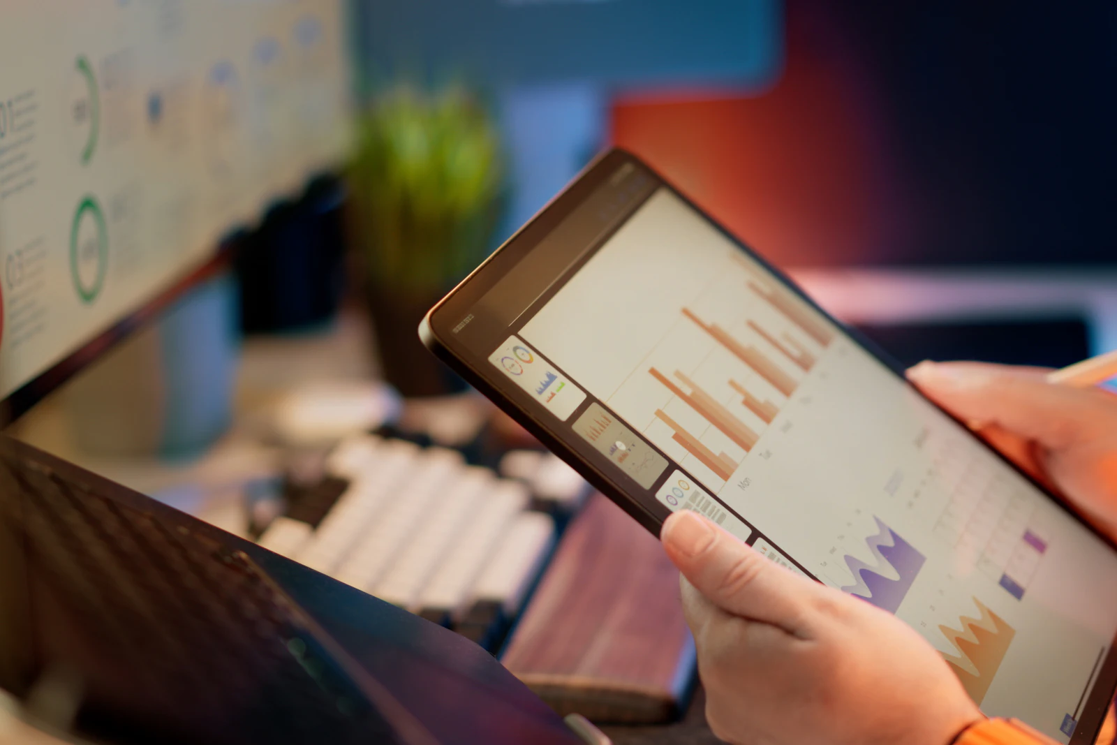 Hands holding a tablet that shows bar and area charts