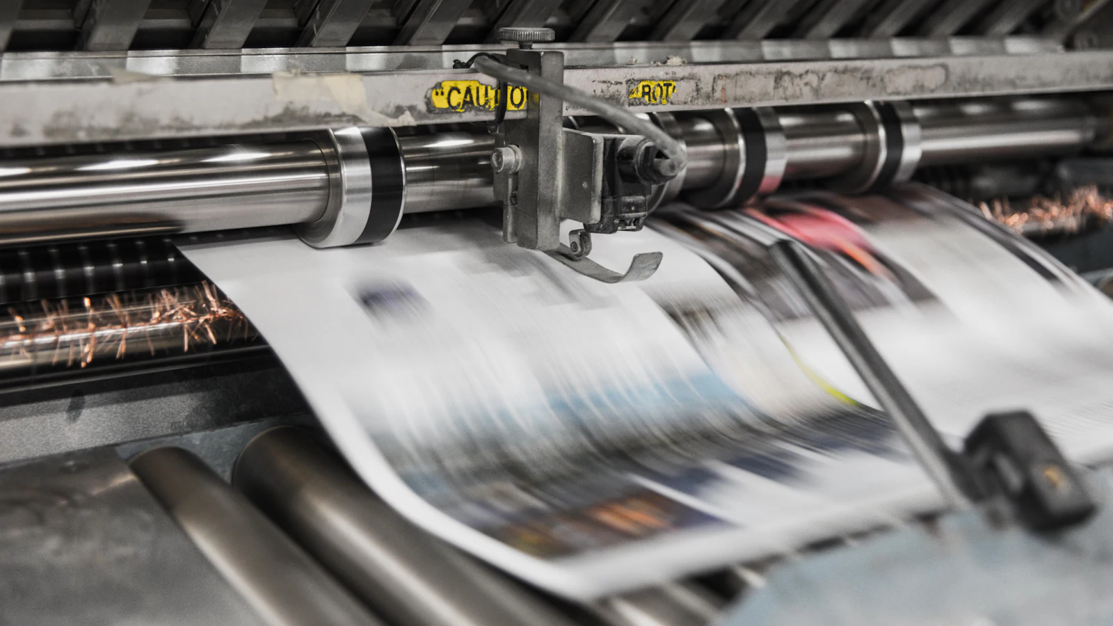 Newspaper pages running through a printing press