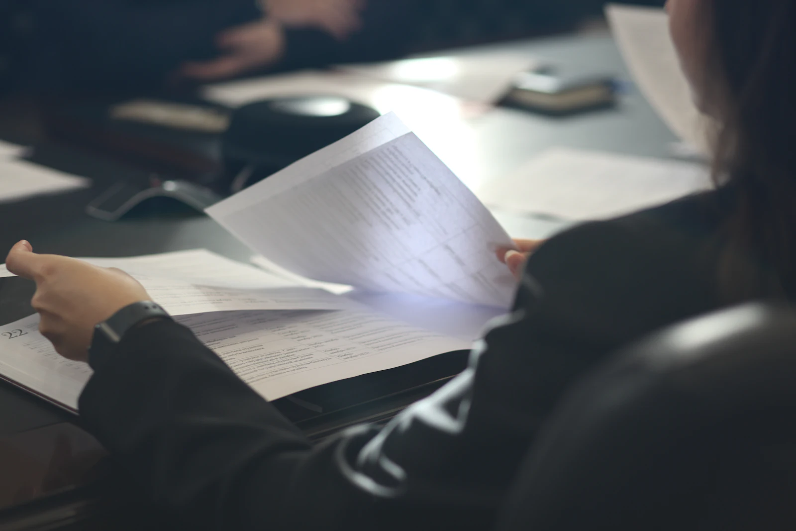 Person reading printed pages at a table