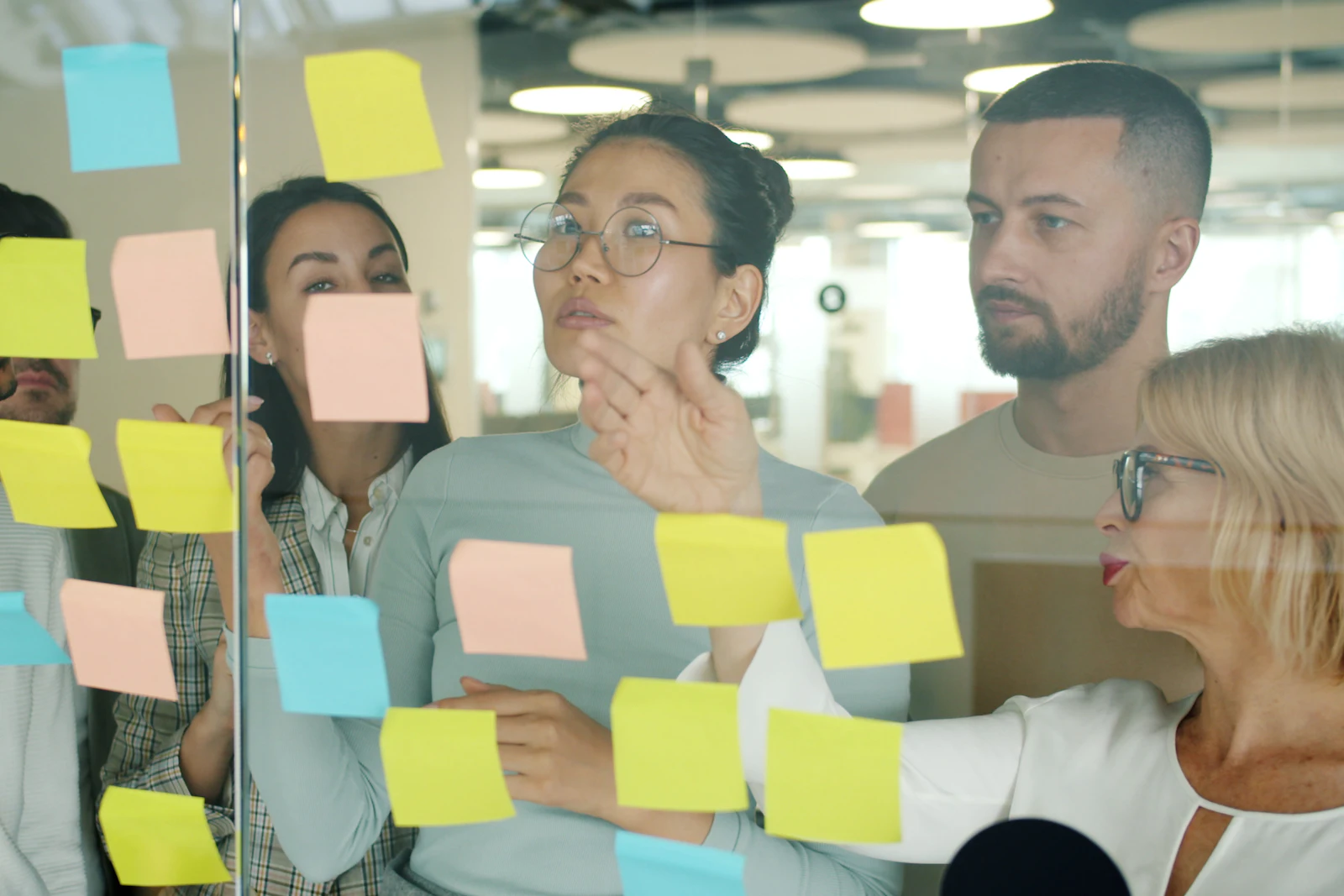 Team arranging sticky notes on a glass wall during a workshop