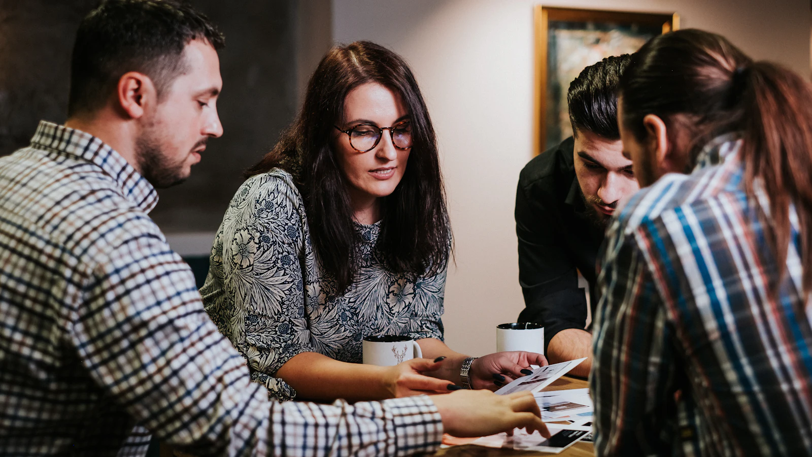 Four colleagues reviewing printouts together around a table